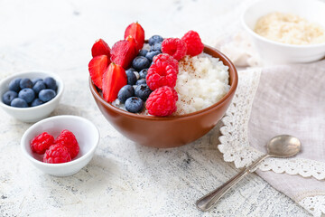 Bowl of tasty rice pudding with berries on light table