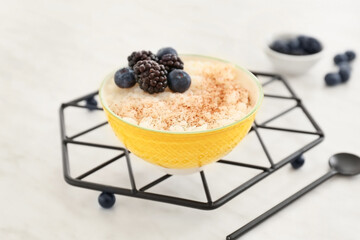 Bowl of tasty rice pudding with berries on white table