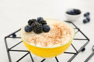 Bowl of tasty rice pudding with berries on white table