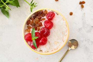 Bowl of tasty rice pudding with raspberry and raisins on white table