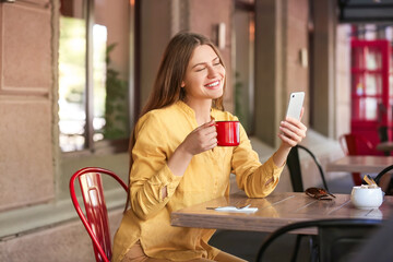 Beautiful young woman taking selfie in outdoor cafe