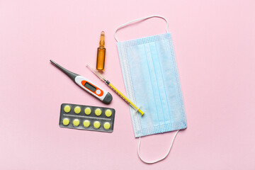 Medical mask, thermometer and cure on color background