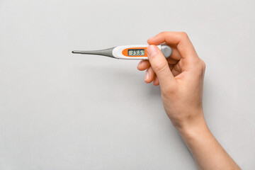 Hand with thermometer on light background
