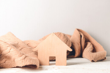 Figure of house and warm scarf on table. Concept of heating season