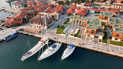Yachts docked on a small port near modern houses