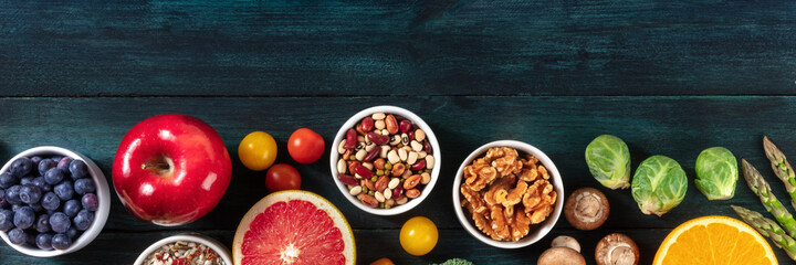Vegan food panorama, top shot with a place for text. Fruit and vegetables, legumes, mushrooms, nuts, a flat lay header, on a dark background