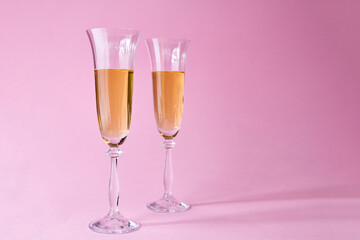 Two glasses of champagne on pink background