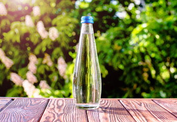 A bottle of drinking water stands on a green natural background
