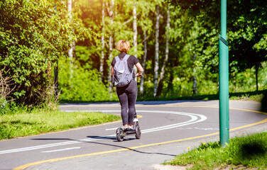 Girl rides an electric scooter in the summer Park
