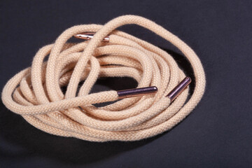 new beige shoelaces with metal lace cap on a black background