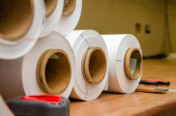 White rolls of PVC film are on the table in the workshop for the production of stretch ceilings....