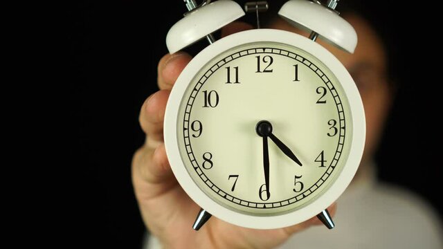 4:30 o'clock. Human hand holding alarm clock that showing four-thirty o'clock and ringing.