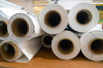 Many white rolls of PVC film are on the table in the workshop for the production of stretch...