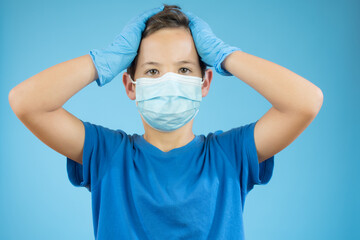 Handsome brunette boy in medical mouth mask over blue background