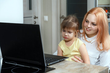 Woman and cute child using laptop. the child is upset and looks at the screen with sadness. baby doesn't want e-learning. online learning difficulties for preschool children