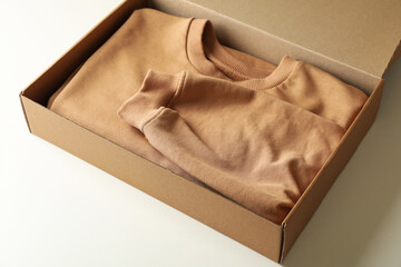 Box with sweatshirt on white background, space for text