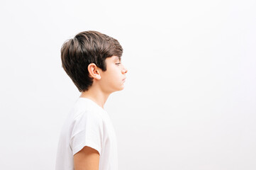 Beautiful kid boy wearing casual t-shirt standing over isolated white background looking to side, relax profile pose with natural face.