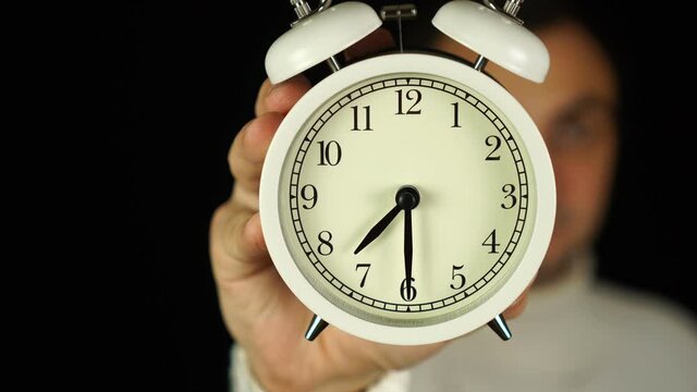 7:30 o'clock. Human hand holding alarm clock that showing seven-thirty o'clock and ringing.