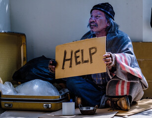 Homless man holds help sign.