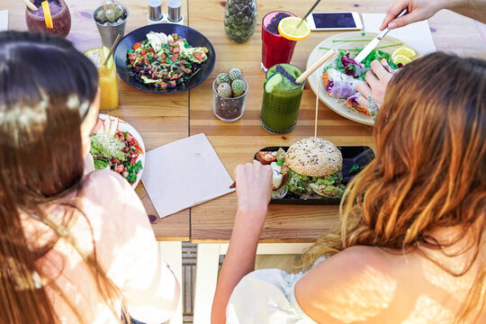 Top view of the vegetarian food, colored smoothie bowl in the bar outdoor. Erasmus students eating in the vegan and vegetarian restaurant. Food, drink and friendly concept. Focus on the table.