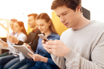 A man looks at phone while sitting with friends.