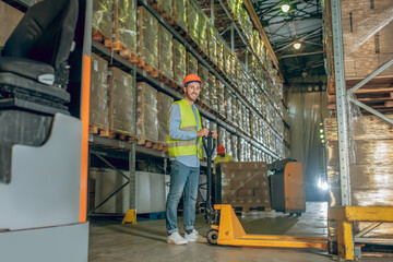 Fototapeta na wymiar Worker in a vest and helmet standing in the warehouse