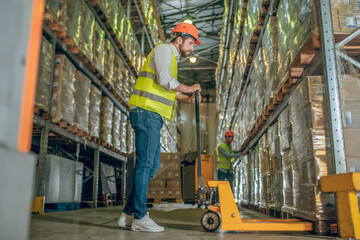 Worker in a yellow vest and helmet standing near the loader