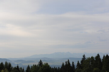 Panorama of mountains  and forested hills with grey sky and clouds in Europe