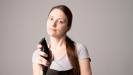 Naklejka premium Young beautiful female hairdresser holding hair clipper