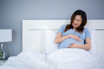 Obraz na płótnie Canvas pregnant woman has a stomachache on bed