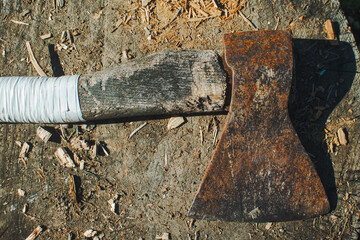 An old ax with a white handle laying on the stump