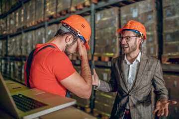 Manager having a conversation with the warehouse worker and looking angry