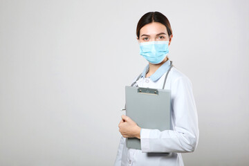Young woman doctor in a protective mask on a light background