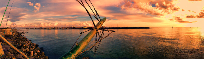 Immersive panoramic golden colored sunset at Tiber river mouth in Rome coast with ruins of old fishing shacks and ropes and suggestive atmosphere © Equatore