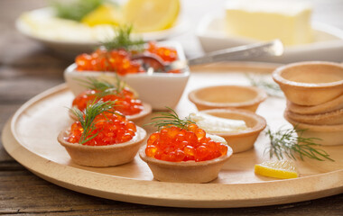 cooking tartlets with red caviar on wooden table