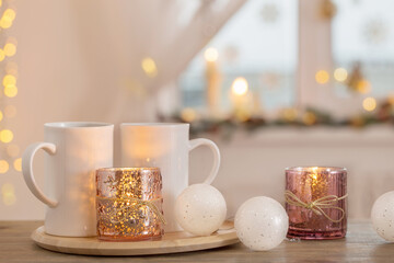 two white cups with christmas decorations on background window