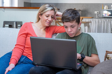 Adolescent et sa mère assis ensemble devant l'écran d'un ordinateur portable