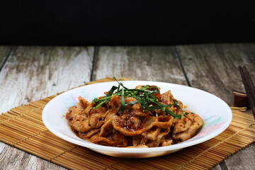 Fried and stirred pork meat with red curry paste and topping with sliced Kaffir lime leaves on the plate. Famous traditional spicy appetizer menu in Asia restaurant. 