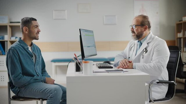 Hispanic Doctor Consultation Office: Male Patient Describes His Complaints, Symptoms to Physician. Health Care Professional Diagnosing Disease, Explaining Test Results, Prescribing Treatment.Side View