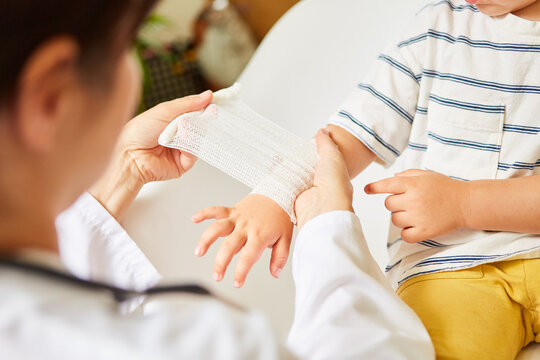 Pediatrician wraps bandage around child's wrist