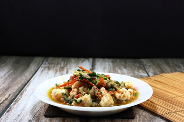 Fried and stirred spicy fresh peeled shrimp with chilly and basil on the plate. Famous traditional appetizer menu in seafood restaurant. 