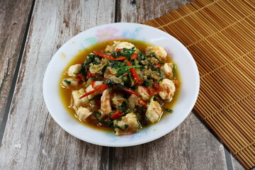 Fried and stirred spicy fresh peeled shrimp with chilly and basil on the plate. Famous traditional appetizer menu in seafood restaurant. 