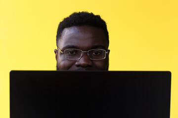 Image of happy excited young african man isolated over yellow background using laptop computer.