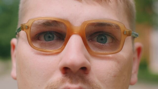 Portrait of serious nerdy man in glasses. A loser teenager is looking to the camera.