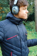 teenager listening to music by headphones, relaxing in autumn city park