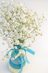 Bouquet gypsophila white tiny  flowers with colorful striped blue vase and ribbon