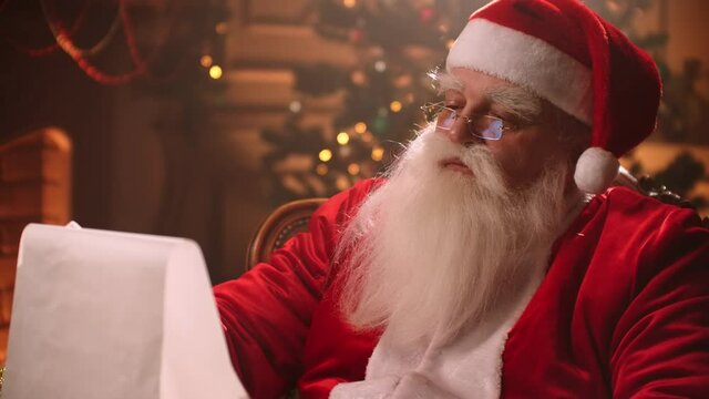 Santa Claus is reading list of good children ad wishes in his residence on North pole, miracle at Christmas holidays