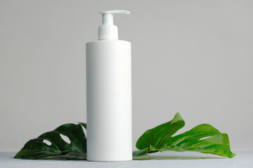 Blank plastic cosmetics container for cream or shampoo. Cosmetics bottle mockup with tropical...