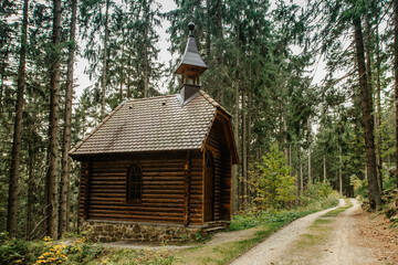 Fototapeta na wymiar Old wooden pilgrimage rural Chapel standing in a forest Czech Republic, Sumava National Park.Boubin Primeval Forest.Czech National Nature Reserve.Outdoors adventure idyllic trekking day.