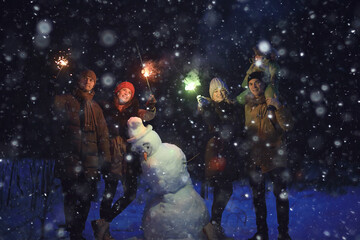 Fototapeta na wymiar group of friends with snowman sparklers party, christmas night and happy new year